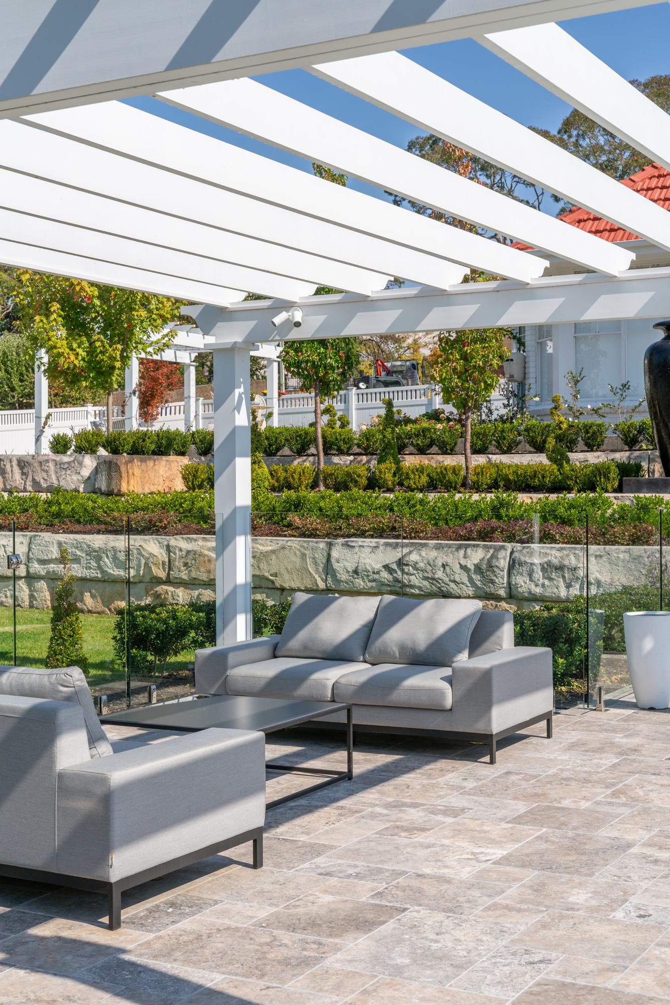 Pergola lounge with outdoor sofa overlooking terraced garden beds