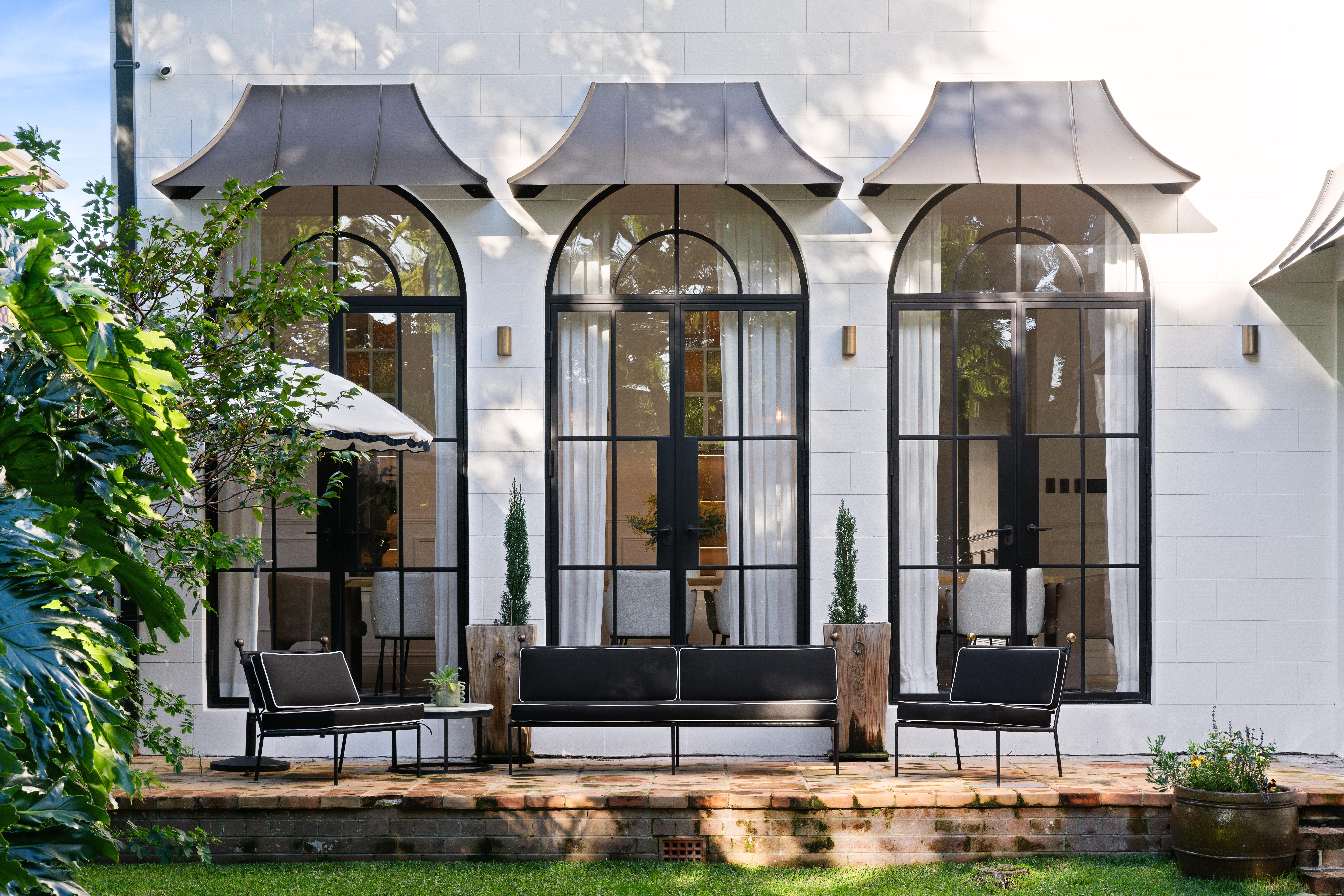 Daylit terrace with arched black-framed doors and outdoor lounge seating