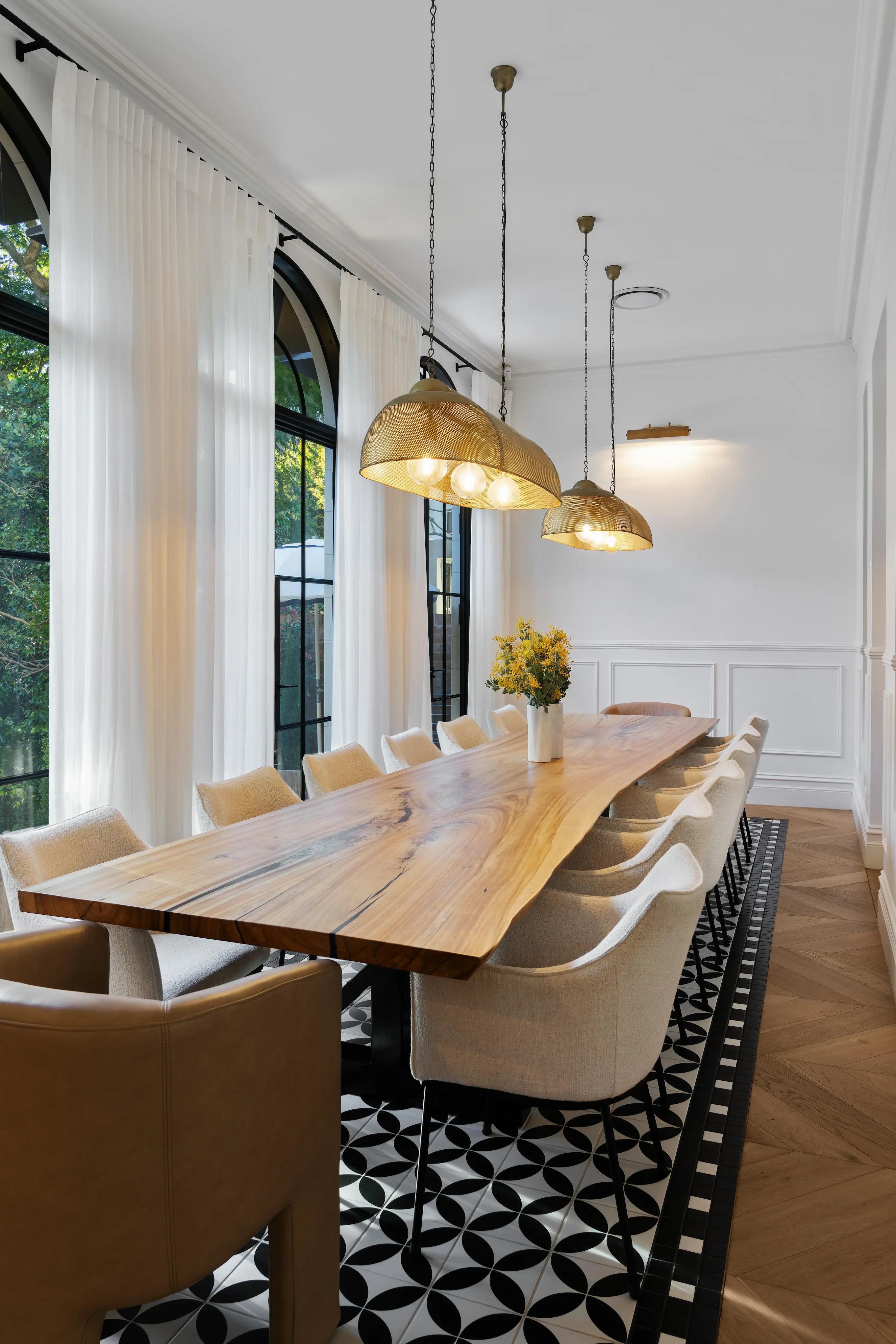 Dining room with live-edge timber table, pendant lights and arched windows