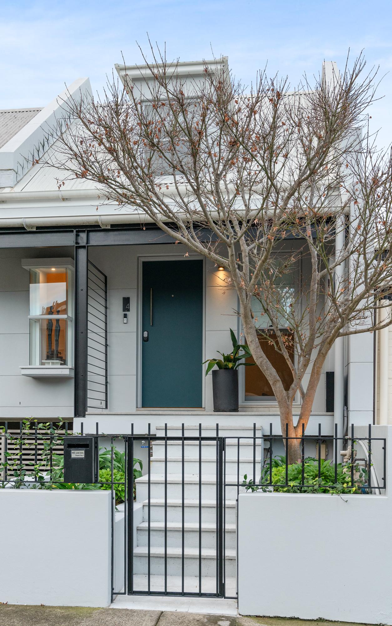 Front elevation of a pale terrace house with dark door and metal gate