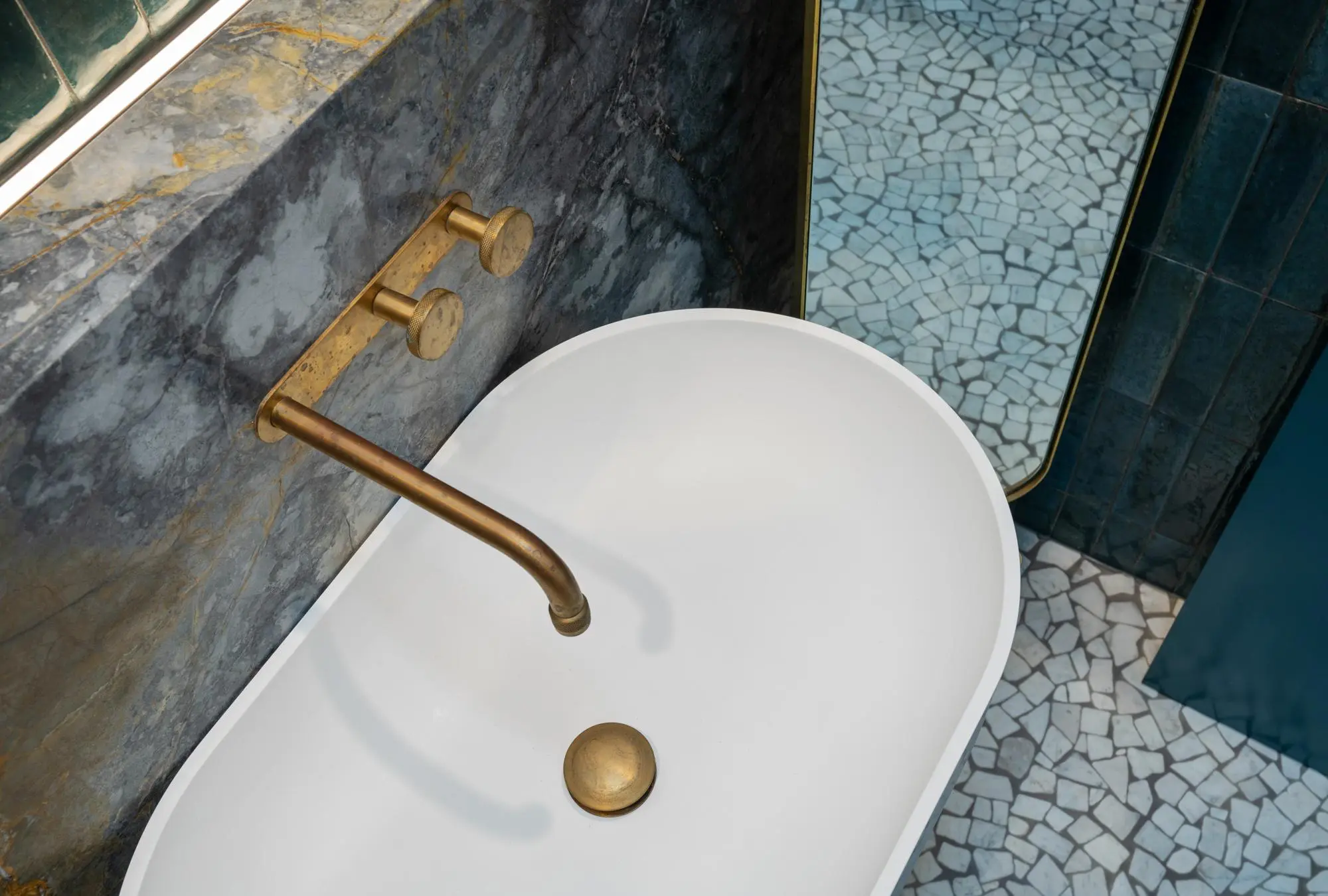 Bathroom vanity with dark marble backsplash and brass wall-mounted taps